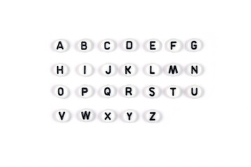 Top view of the English alphabet made of white beads with the English alphabet scattered on a white...
