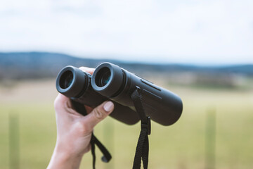 female hand holding a binoculars .