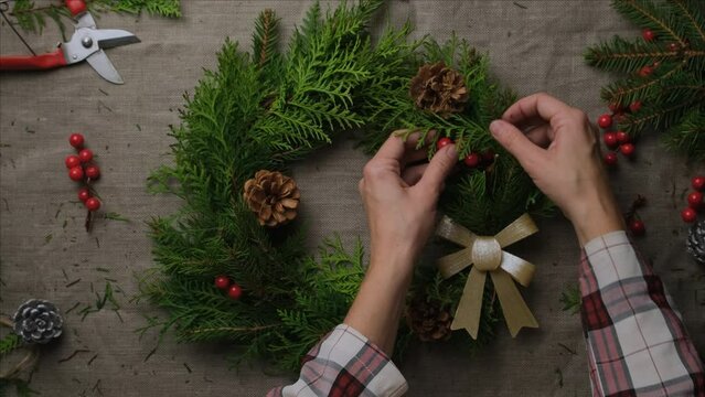 Hands making Christmas wreath. DIY Xmas home decor. 