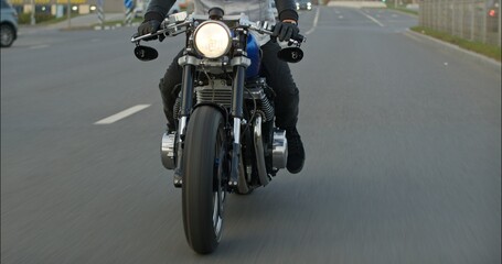Close-up of a motorcycle riding on a road at high speed. Side view. Driving Bike on Streets. Speed Motion in Cityscape. Fast TRACKING Shot of a biker riding his custom built cafe racer through city.