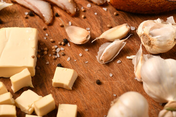 still life of food in a rural style on a dark wood background, sliced cheese, garlic, salt and pepper, concept of healthy food