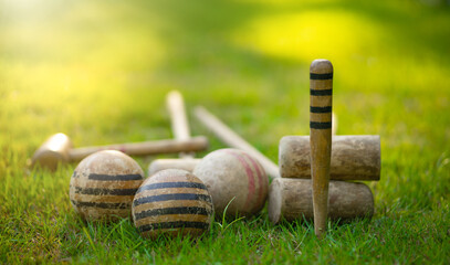 An antique set for playing croquet on the green grass. Wooden clubs with striped balls. Victorian...
