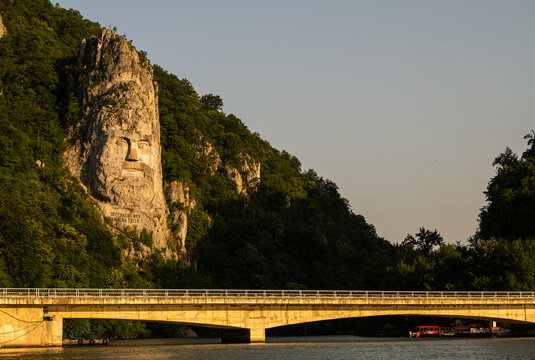 Decebal Head sculpted in rock and photographed during a summer sunrise in Danube Gorges landmark from Romania.