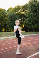 Child girl warming up on the sports track before running