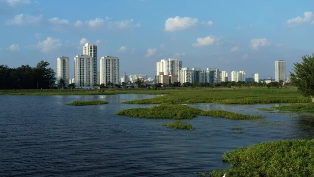 Aerial drone dolly-in and rising shot of the south part of S&atilde;o Paulo, Brazil from the man-made Guarapiranga Reservoir towards the Socorro neighborhood with skyscrapers and houses on a fall evening