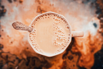 Top view of a gray mug of warm, pleasant cocoa with a teaspoon with patterns. Breakfast.