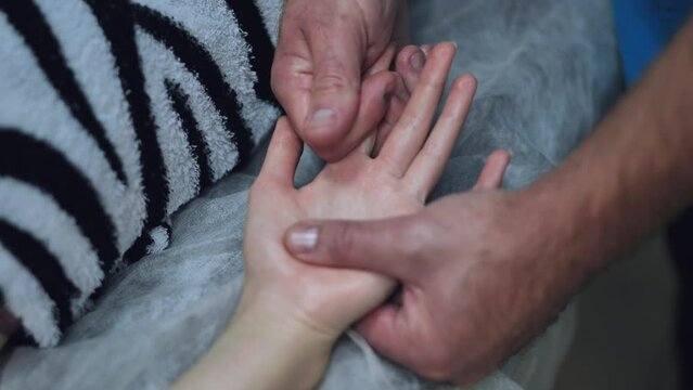 A masseur massages the wrists of a girl.