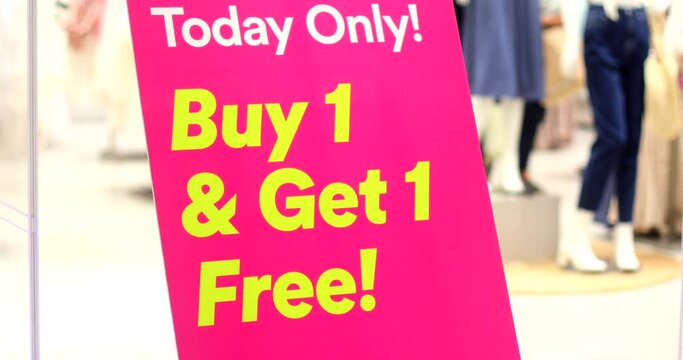Bright pink sign with yellow words Buy 1 Get 1 Free in shopping mall