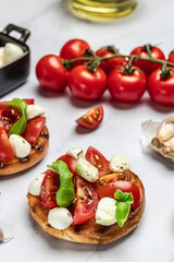 Caprese toasts with mozzarella, cherry tomatoes and fresh garden basil. Traditional italian appetizer or snack, antipasto. vertical image. top view. place for text