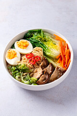 Ramen noodle soup with eggs, mushrooms, pak choi in white bowl