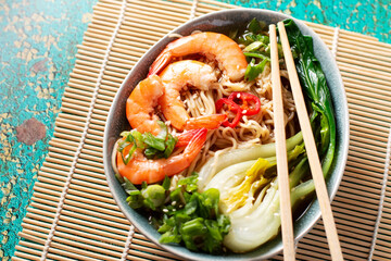 Ramen noodle soup with shrimp, green shallot, pak choi on green background