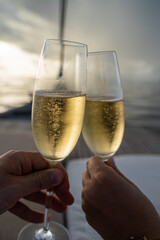 Anstoßen mit Champagnerglas / Sektglas mit prickelndem Sekt während einer Bootsfahrt auf den...