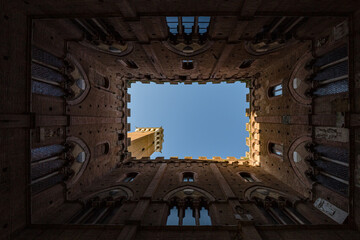 Fototapeta na wymiar Siena, Italy – may, 2022: view of sky from internal court in Palazzo Pubblico Siena, Italy. Bell tower- Torre del Mangia 