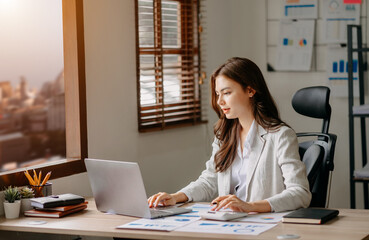 Young beautiful woman using laptop and tablet while sitting at her working place. Concentrated at work..