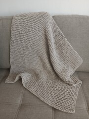 Knitted grey blanket on sofa