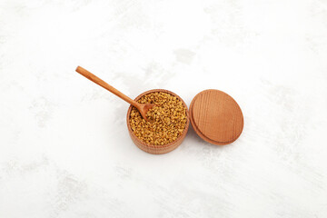 Fenugreek seeds in wooden bowl, top view. Healthy seeds of plant Trigonella foenum-graecum. Used for drinks, in culinary and alternative medicine