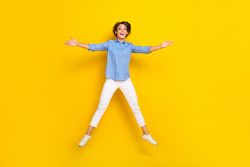 Fototapeta na wymiar Full length photo of pretty sweet lady wear blue shirt arms jumping high like star isolated yellow color background