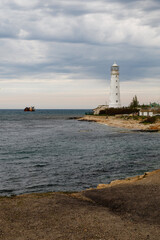 Old white lighthouse on Cape Tarkhankut and a sunken ship in the sea