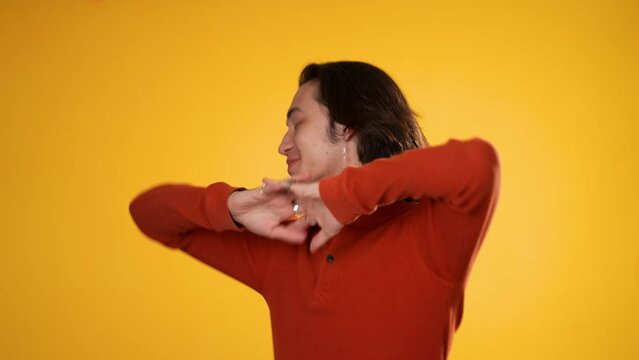 Portrait of happy smiling dancing Hispanic Latino gender fluid non-binary man isolated on yellow background.