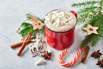 Red cup of hot cocoa with marshmallows and candy canes on with christmas tree