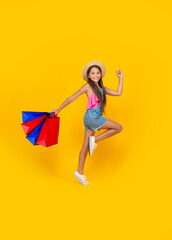 happy teen kid run with shopping bags on yellow background. full length