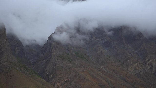4K shot of fog around the mountain peaks during the stormy weather at Tandi in Lahaul Spiti district at Himachal Pradesh, India. Clouds rolling over the peaks of the mountain. Nature background. 