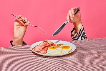 Foto op Aluminium Female hands with fork and knife eating English breakfast with fried eggs and bacon © master1305