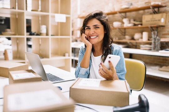 Happy Online Store Owner Using A Smartphone In A Warehouse