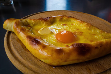 Traditional Georgian cuisine - Adjarian khachapuri on a wooden board. Ready-to-eat baking