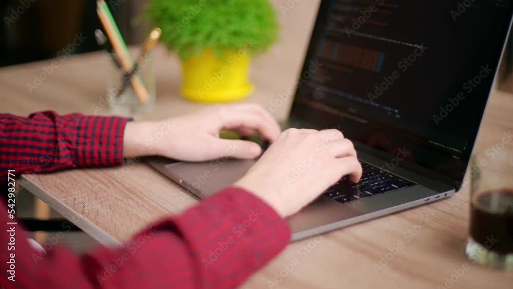 Wall mural close up of freelancer's hands typing code on laptop keyboard. camera slides around developer's fige
