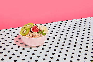 Plate of delicious oatmeal made on milk with fresh fruits, kiwi and banana on pink background