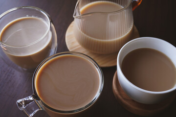 Several cups of hot coffee and milk on a wooden table - 542983949