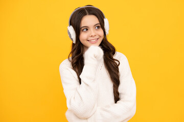 Modern teen girl wearing sweater and winter warm earmuff ear-flaps hat on isolated yellow background.