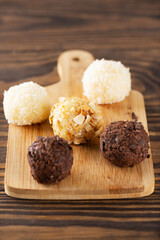 Traditional Brazilian candy brigadeiro truffles with chocolate and coconut on a wooden board.