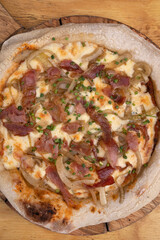 Pizza background. Closeup view of a pizza with tomato sauce, mozzarella cheese, crispy bacon and onions, with a wooden background.