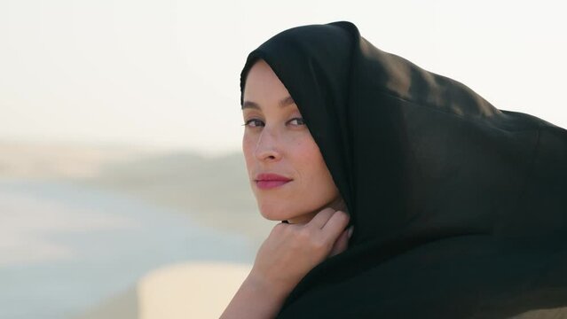 Portrait of beautiful young Arab muslim woman in traditional black hijab. At Doha Qatar. Close up of female joyful face. Arabian headscarf. Outdoor.
