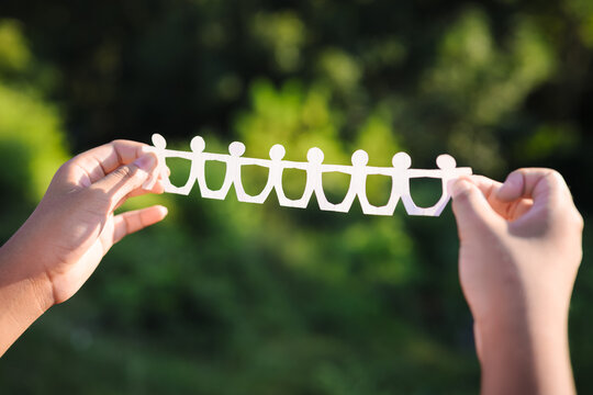 Closeup child's hands show the paper human chain in the forest, human and environment concept, CSR, teamwork in nature
