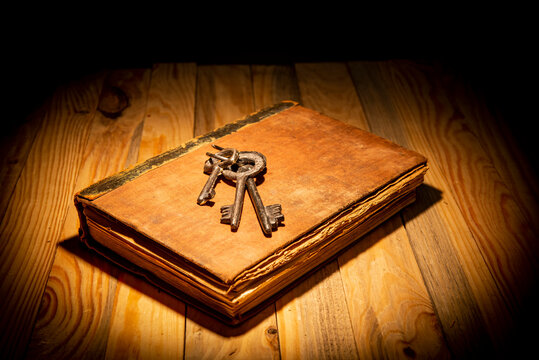 Vintage book with old keys on dark table top - education and knowledge theme