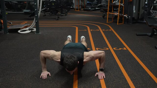 Athlete performing clap pushup from plank position in fitness gym