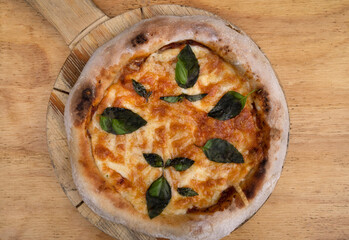Traditional Margherita pizza. Closeup view of a pizza with mozzarella and parmesan cheese, tomato sauce and basil, on the wooden table.