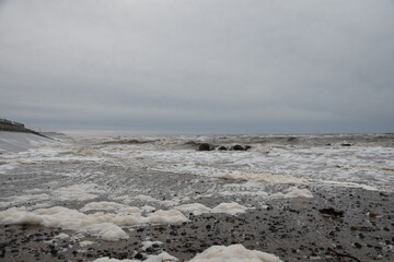 Large waves crashing onto the beach during a storm with a dramatic sky background. Taken in Cleveleys Lancashire England. 
