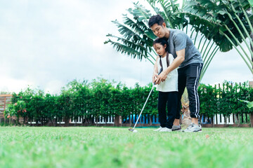 Happy asian family in the garden, Father and doughter. They are having fun playing golf in home...