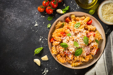 traditional italian kitchen. Italian pasta alla arrabiata with basil and parmesan on dark table. Top view with copy space.