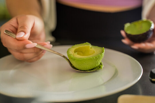 Cropped view of the female person holding avocado on the spoon
