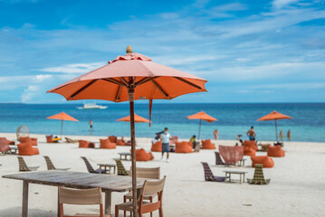 Orange wicker rattan chairs and matching parasols dot the beachfront of a posh resort in Dumaluan...