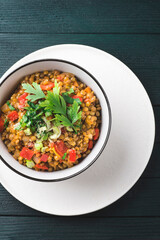 Lentil soup or medieval legumes pottage with stew vegetables in bowl on rustic kitchen green wooden table . Vegan food legumes for healthy diet, ancient recipes, close-up