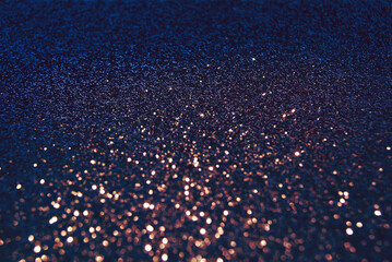 Dark blue de focused sparkle glitter background with golden particles close up