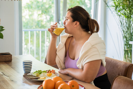 Brunette woman drinking juice and looking at the window while eating tasty food - Powered by Adobe