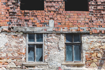 Damaged home with bricks and broken windows. Ruins of a construction after a tragedy