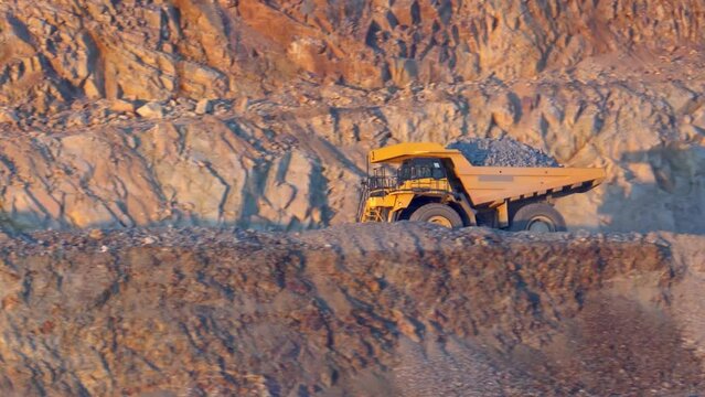 Heavy mining dump trucks driving along the opencast open mine pit, slow motion